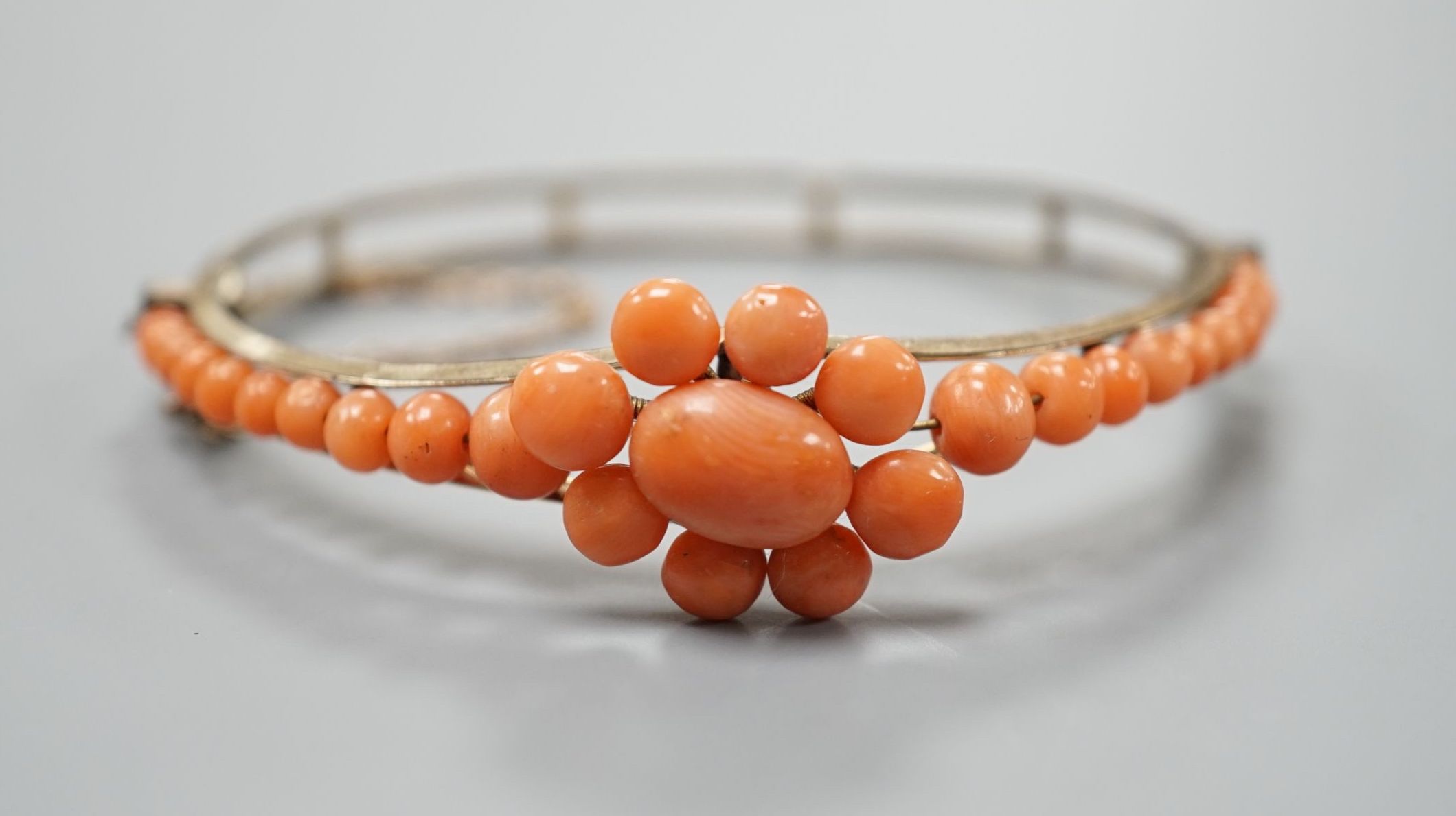 A gold plated and coral bead cluster set hinged bangle.